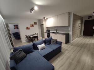 a living room with a blue couch and a kitchen at Apartament Bukowy in Wejherowo