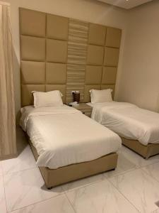 duas camas num quarto de hotel com lençóis brancos em روز للشقق الفندقية 2 em Al Kharj
