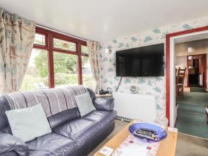 a living room with a couch and a flat screen tv at Blairgorm Croft in Nethy Bridge