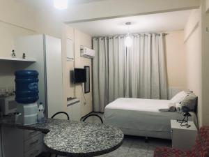 a small hotel room with a bed and a table at Stúdio Beira Mar in Fortaleza