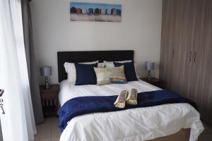 ein Schlafzimmer mit einem Bett mit zwei Schuhen drauf in der Unterkunft OR Tambo Self Catering Apartments, The Willows in Boksburg