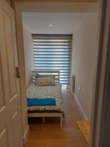a bedroom with a bed and a window with blinds at Vibrant Single Room only for one adult in Southall
