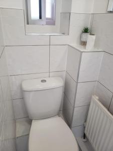 a white bathroom with a toilet and a window at Vibrant Single Room only for one adult in Southall