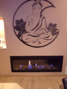 a picture of a buddha sitting in a room with a fireplace at chambre avec spa privatif in Loon-Plage