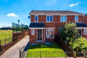 a brick house with a fence in front of it at Stylish 4 bedroom home close to Manchester City centre in Manchester