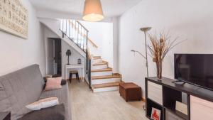 a living room with a couch and a tv and stairs at La Malagueña Rincón de la Victoria by Ruralidays in Rincón de la Victoria