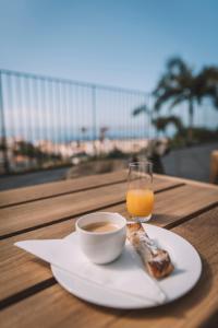 een bord met een kopje koffie en een glas sinaasappelsap bij Torrinha Garten Apartment in Funchal