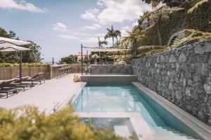 a swimming pool with a stone wall next to a stone wall at QUINTA TORRINHA GARDEN Apartment in Funchal