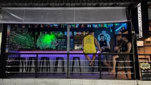 un hombre parado en un bar con dos personas sentadas en él en Loft Hostel Koh Tao, en Ko Tao