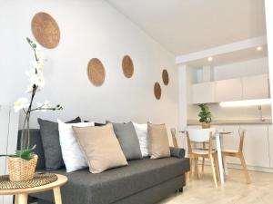 a living room with a gray couch and a kitchen at Castro Holidays - Apto A Céntrico Terraza con Garaje Gratis in Castro-Urdiales