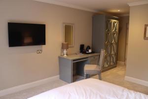 a hotel room with a bed, desk and television at Rafters at Riverside House Hotel in Bakewell