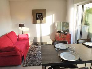 un soggiorno con divano rosso e tavolo di appartement entre golf, plages ,marina a Mandelieu La Napoule