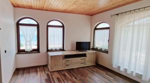 a living room with three windows and a television at Casa de Marinero Villa in Fish Fish