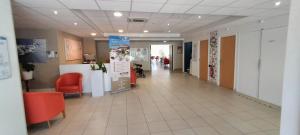 a hospital hallway with red chairs and a waiting room at Villa Rose de Mons - Résidence Services Senior in La Brede