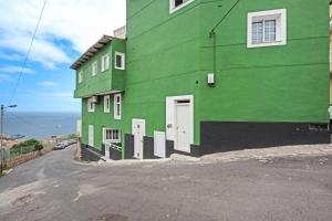 un edificio verde al lado de una calle en Casita Auxilia, en Araya