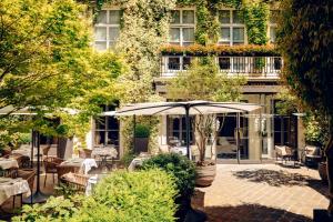 un patio avec des tables et des parasols en face d'un bâtiment dans l'établissement Le Pavillon de la Reine & Spa, à Paris