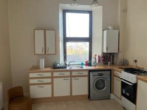 Lovely one bedroom Apartment in Glasgow City في غلاسكو: مطبخ مع مغسلة وغسالة ملابس