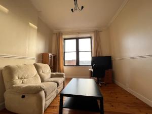 Lovely one bedroom Apartment in Glasgow City في غلاسكو: غرفة معيشة مع أريكة وطاولة قهوة