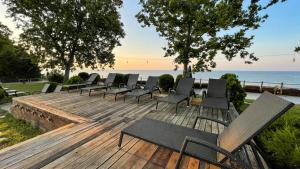 una fila de sillas en una terraza de madera con vistas al océano en PİA MARE OTEL, en Gündüzlü