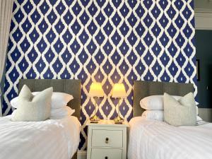 two beds in a room with blue and white wallpaper at Barriemore Oban in Oban