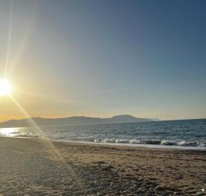 uma praia com o sol nascendo sobre o oceano em Olive Tree Farm 200m from the beach em Episkopi- Rethymno