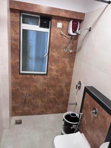 a bathroom with a toilet and a window at Pinaki Comfort Stay, Vile Parle in Mumbai