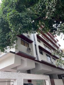 een wit appartementencomplex met een balkon en bomen bij Pinaki Comfort Stay, Vile Parle in Mumbai