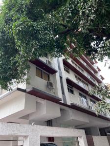 a white apartment building with a balcony and trees at Pinaki Comfort Stay, Vile Parle in Mumbai