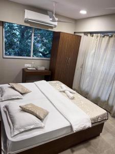 a bedroom with a bed with white sheets and a window at Pinaki Comfort Stay, Vile Parle in Mumbai