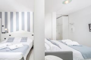 2 letti in una camera bianca con specchio di Hotel Bellavista a Lignano Sabbiadoro