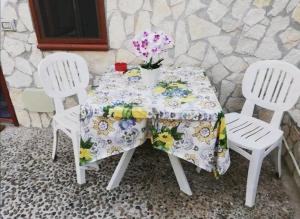 een tafel met twee witte stoelen en een tafel met bloemen erop bij La Gallizza in Cefalù