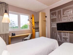 um quarto com 2 camas, uma secretária e uma televisão em ibis Igrejinha em Igrejinha