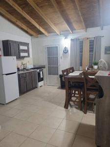 Il comprend une cuisine équipée d'une table et d'un réfrigérateur blanc. dans l'établissement Villa zoe house near rincon, à Anasco