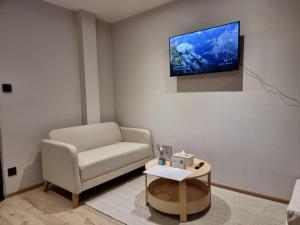 a living room with a couch and a tv on the wall at The Nhorm Hotel Ratchada in Bangkok