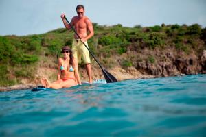 a man and a woman on a surfboard in the water at Divi Little Bay Beach Resort in Philipsburg