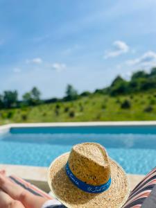 a straw hat sitting on a chair next to a pool at Magnifique gîte au coeur d'une truffière in Le Garn