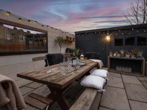 een patio met een houten tafel en een open haard bij Stow House in Stow on the Wold