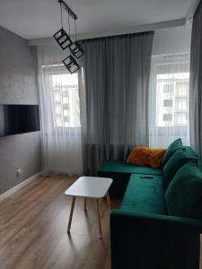 - un salon avec un canapé vert et une table dans l'établissement Apartamenty Termalne na Długiej 6, à Uniejów