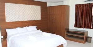 a bedroom with a white bed and a wooden headboard at A and M Rooms and Residences in Chennai