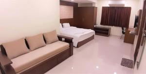 a hotel room with a couch and a bed at A and M Rooms and Residences in Chennai