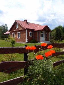 a house with red flowers in front of a fence at Jałówka - odpocznij na Podlasiu in Jałówka