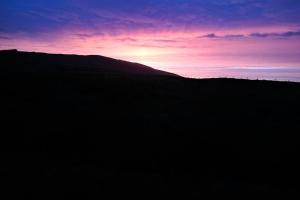 einen Sonnenuntergang über einem Hügel mit Sonnenuntergang hinter einem Berg in der Unterkunft Skellig View Bluebell Rose & The Kerry Cliffs in Portmagee