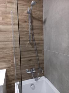 La salle de bains est pourvue d'une douche et d'une baignoire blanche. dans l'établissement Apartamenty Termalne na Długiej 6, à Uniejów
