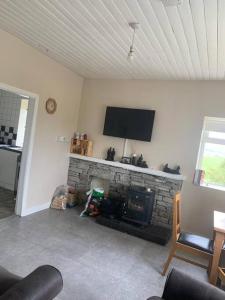 un soggiorno con camino e TV sopra di Ballyliffin Quaint Irish Cottage overlooking Malin Coast a Clonmany