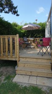 a wooden deck with a table and an umbrella at Mobil home 6-8 places Parcelle 4 climatisé in Biville-sur-Mer