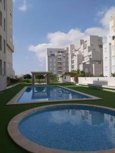 a large swimming pool in a city with buildings at Appartement 1ch Romantique Vue sur Piscine in Nabeul