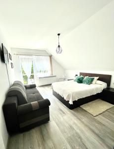 a white bedroom with a bed and a couch at U Gosi Zator in Zator