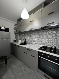 a kitchen with white cabinets and a stove top oven at New Residence Apartament in Popeşti-Leordeni