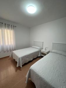 una camera con due letti e una luce sul soffitto di Apartamento Cristina 3D a Morro del Jable