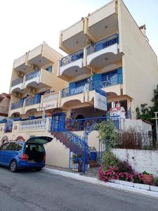 a car parked in front of a building with blue balconies at Alexia House in Neos Marmaras